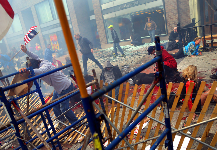 Boston-4/15/13- Carlos Arredondo(left) climbs over the barricades on Boylston Street to get to the injured on the sidewalk at the site of the first bombing near the finish line at the Boston Marathon.