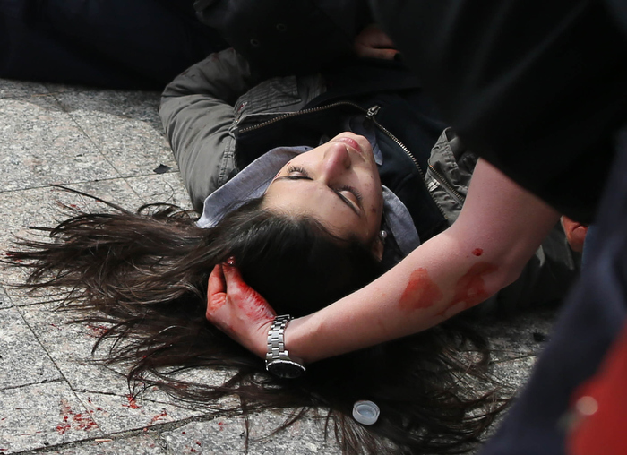 Boston-4/15/13- A man comforts a woman who was hit by shrapnel from the first terrorist bomb on the sidewalk near he finish line of Boylston Street.