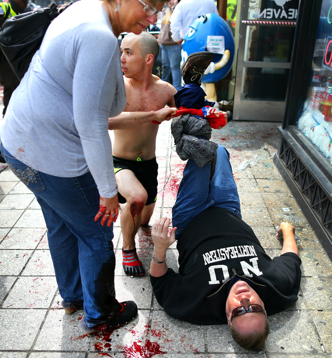 Boston-4/15/13- Robert Wheeler, a runner in the Boston Marathon took off his shirt and put in around the leg of injured spectator Ron Brassard as his wife Karen, also injured in the legs, looks on. They were standing on the Boylston Street sidewalk near the finish line when they were hit with shrapnel from the first terrorist bomb.