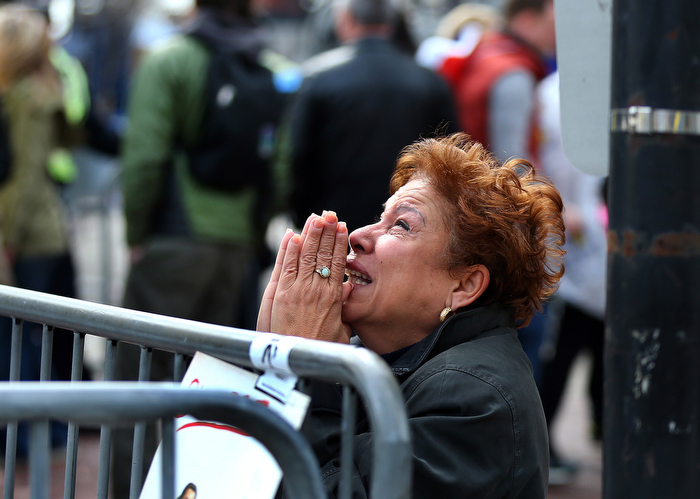 Boston-4/15/13- A woman kneels and prays at the scene of the 1st explosion on Boylston Street At the finish line of the Boston Marathon,