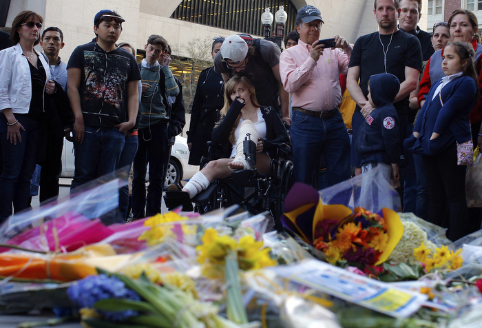 A Boston Marathon bombing survivor (C) visits the site of the first bomb explosion on Boylston Street in Boston, Massachusetts April 24, 2013.