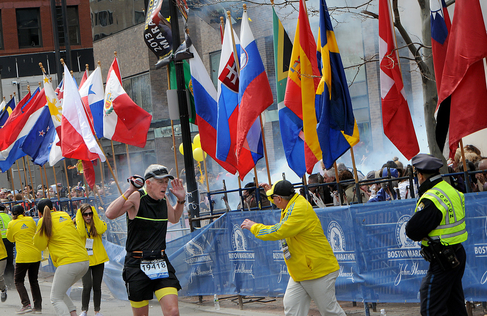 Runners, marathon officials and police react as a bomb explodes just a few yards from the finish line of the Boston Marathon on Monday, April 15, 2013.
