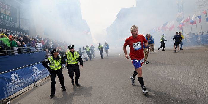 As smoke fills Boylston Street, a runner reaches the finish line and police begin to react moments after a bombing at the finish line of the 2013 Boston Marathon.