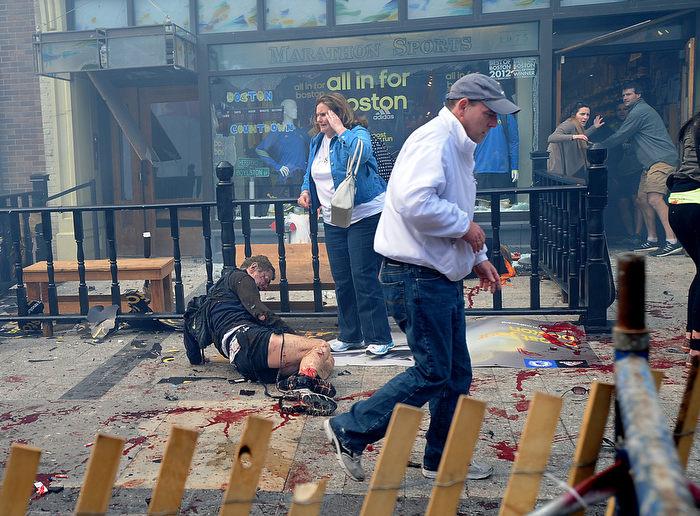 Injured spectators lie in the sidewalk as bystanders begin to react in front of Marathon Sports on Boylston Street in Boston shortly after a bombing yards away at the Boston Marathon finish line.