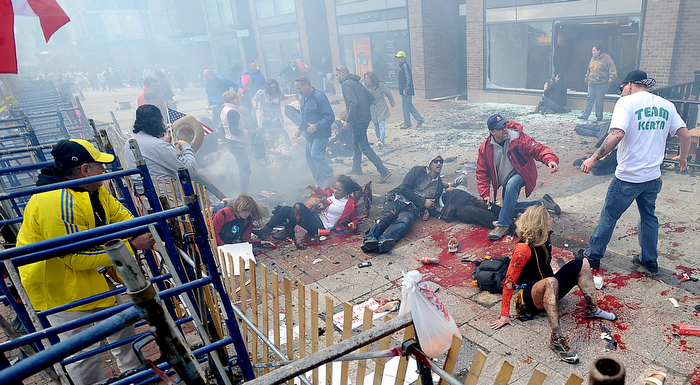 Smoke hovers over a chaotic scene of injured people and spectators along Boylston Street in Boston, just yards from the Boston Marathon finish line, after a bombing on April 15, 2013.