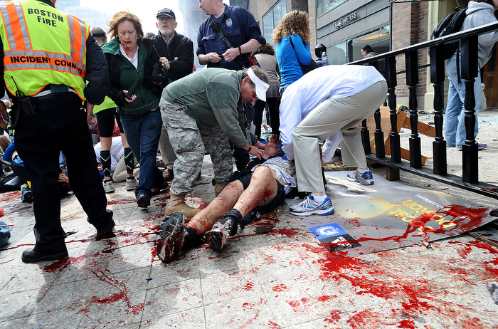 Good Samaritans tend to injured spectators on the sidewalk of Boylston Street in Boston after a bombing near the finish line of the Boston Marathon on Monday, April 15, 2013. Three people were killed and over 200 injured in the attacks.