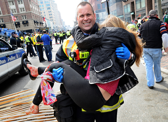 Boston Firefighter James Plourde carries Victoria McGrath, 20, an injured spectator, from the scene of the Boston Marathon bombing on Boylston Street on Monday, April 16, 2013. Plourde was working a fire department detail near the finish and rushed to the scene immediately after the explosions.