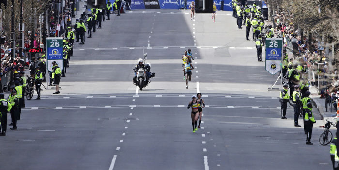 With a heavy presence of security, Boston police officers line Boylston Street as the lead men's runners head down towards the finish line at the 26th mile mark during the 2013 Boston Marathon in Boston, Monday, April 15, 2013.