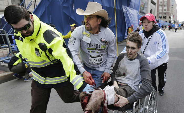 Boston Marathon survivor Jeff Bauman is wheeled from the site of an explosion near the finish line of the Boston Marathon by medical volunteer Devin Wang, as bystander Carlos Arredondo and EMT Paul Mitchell keep Bauman from bleeding out, Monday April 15, 2013.