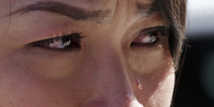 Boston Marathon runner Vu Trang, of San Francisco, cries at a makeshift memorial on Boylston Street near the finish line of Monday's Boston Marathon explosions, which killed at least three and injured more than 260, in Boston, Wednesday, April 17, 2013. The bombs that blew up seconds apart near the finish line left the streets spattered with blood and glass, and gaping questions of who chose to attack at the Boston Marathon and why.