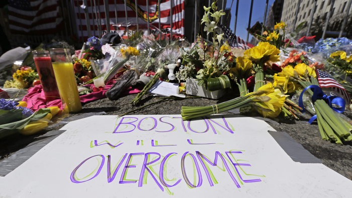 Flowers and signs adorn a barrier at Boylston Street near the of finish line of Monday's Boston Marathon explosions, which killed at least three and injured more than 140, in Boston, Wednesday, April 17, 2013.