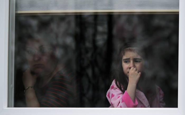 A girl looks out the window of her family's home as a SWAT team drives through her neighborhood while searching for a suspect in the Boston Marathon bombings in Watertown, Mass., Friday, April 19, 2013.
