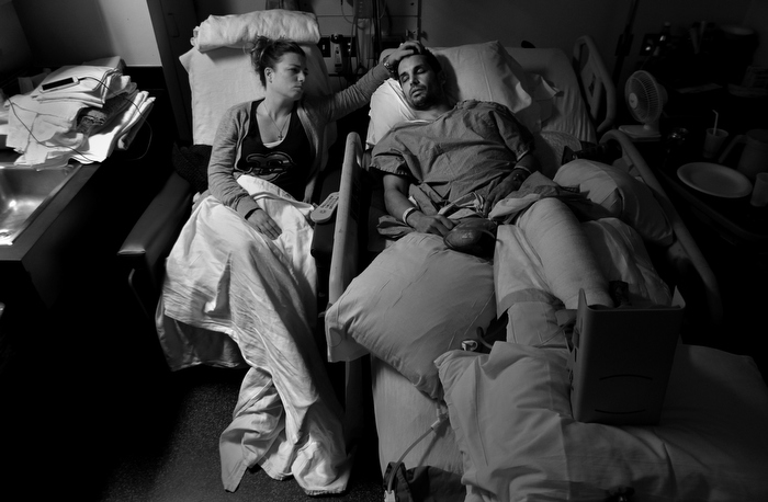Jen Regan, fiance of Boston Marathon bombing victim Marc Fucarile, strokes his forehead as he lay asleep in his hospital bed in Massachusetts General Hospital following his 7th surgery, three weeks after the attack. His right leg was amputated and the remaining one is badly damaged with a broken knee, shattered foot, third degree burns, and shrapnel wounds.