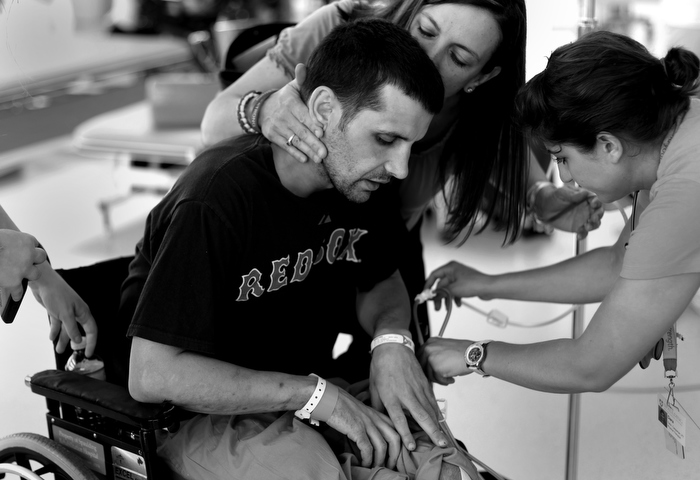 Marc gets a kiss from sister Stephanie Baron while receiving physical therapy in the gym at the Spaulding Rehabilitation Hospital. "He'll be home soon," she says. It's what everyone has been telling him. Doctors, friends, family. Focus on getting home and the rest will come.
