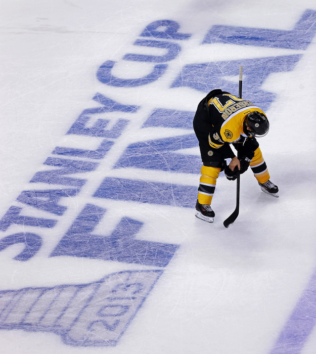 The Bruins Patrice Bergeron is bent over in despair as the Blackhawks continue to celebrate at the other end of the ice.