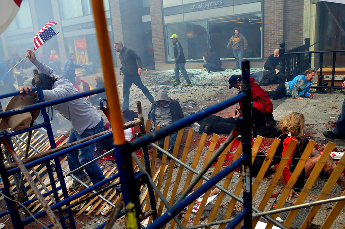 Boston-4/15/13- Carlos Arredondo (left) climbs over the barricades on Boylston Street to get to the injured on the sidewalk at the site of the first bombing near the finish line at the Boston Marathon.