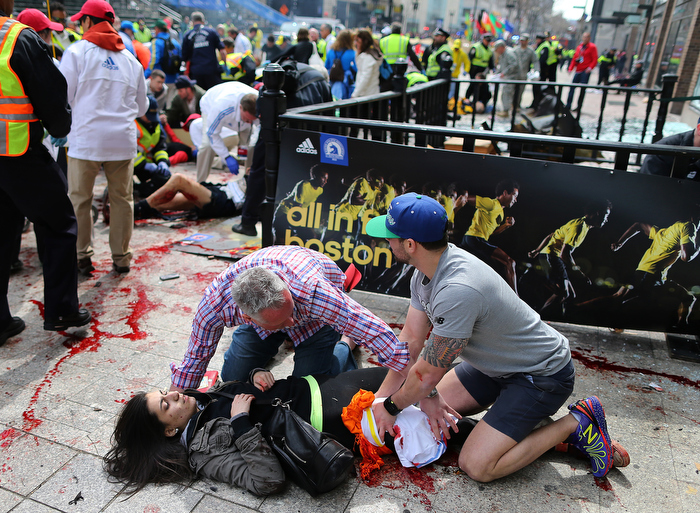 Boston-04/15/13- Sydney Corcoran from Lowell is helped by Matt Smith (left) from Boston and Zack Mione from Portland, Oregon on the sidewalk at the site of the first Boston Marathon bombing. They saved her life by applying pressure to her wounded leg and using t-shirts as a turniquet.