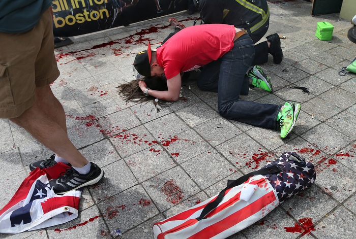 Boston-4/15/13- Joe Duncan, a Marine, comforts a woman who was hit by shrapnel from the first terrorist bomb on the sidewalk near the Boston Marathon finish line of Boylston Street.