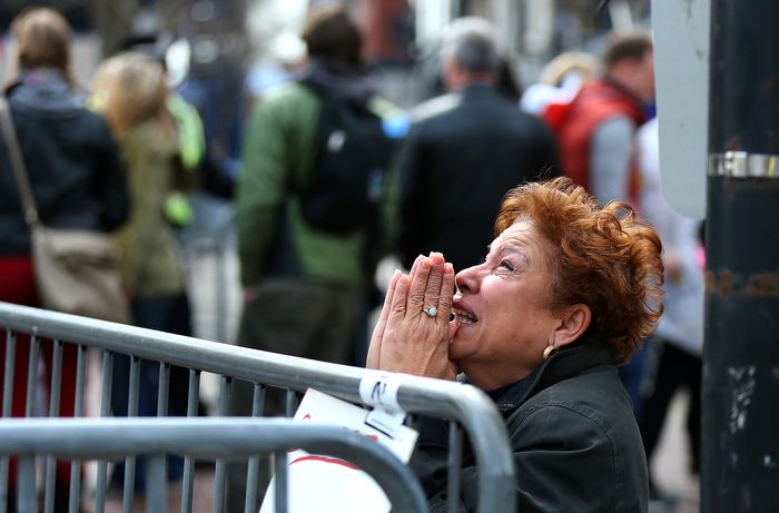 Boston-4/15/13- A woman kneels and prays at the scene of the first explosion on Boylston Street At the finish line of the Boston Marathon.