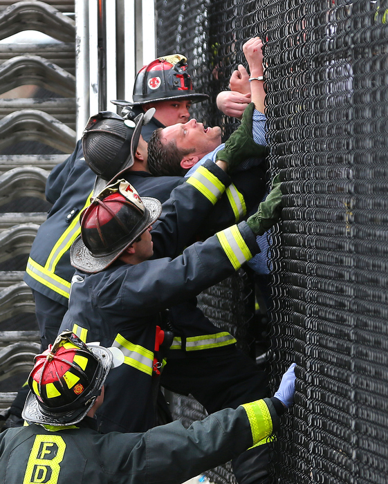 Boston-4/18/13- A man was rescued by Boston Firefighter on an aerial ladder assisted by Boston EMS. Police responded to a report of a man carrying a backpack threatening to jump off the bridge at Washington Street in Chinatown that goes over the MassPike. Traffic was stopped on the Pike so the firetruck could raise it's ladder from below. He was handcuffed to the fence and a hole was cut into the fence to bring him to the street. His backpack fell to the MassPike and was searched.