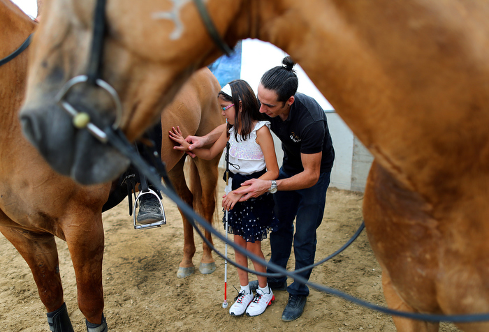 Somerville-09/11/13 Joicee Gordillo, 11 is blind and with the help of Dorian Escalon was able to feel one of the horses in the stables at Cavalias Odysseo. Escalon is one of the riders in the show, and Gordillo visited the stables with a group of visually impaired students.