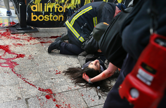 Boston-5/03/13- Sydney Corcoran from Lowell, Massachusetts lies next to her trail of blood as she is comforted on the sidewalk at the site of the first Boston Marathon bombing. She was standing with her mother Celeste and father Kevin to cheer on her aunt was was running. A piece of shrapnel the size of a cell phone from the pressure-cooker bomb severed her femoral artery. She nearly bled to death. She fell fifteen feet away from her mother who lost both legs in the bombing.