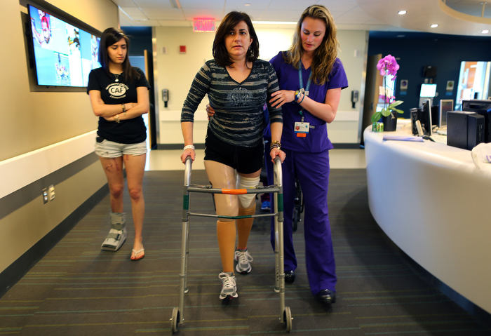 Boston-06/20/13- Celeste Corcoran walks on her two new prothesis at Spaulding Rehab. She lost both legs in the first Marathon bombing. She is helped by physical therapist Alyson Jodoin as her daughter Sydney(l) who was also severely injured walks with them. "They just feel so unnatural. It feels like you're walking on stilts." Celeste said.