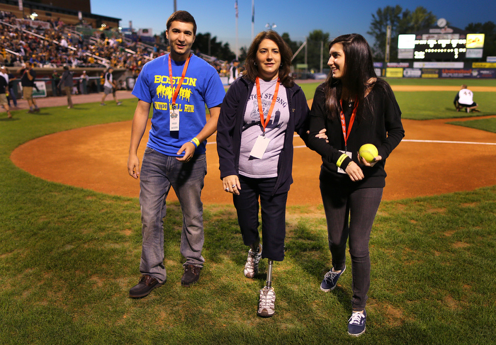 Lowell--09/05/2013 Celeste Corcoran holds the arm of her daughter Sydney as they elk with her son Tyler off walks off the Lowell Stadium baseball field after she and Sydney threw out the first pitch in a benefit softball game. Celeste, despite having getting new state of the art prosthetics, still needs to be helped with her balance as she gets tired walking.