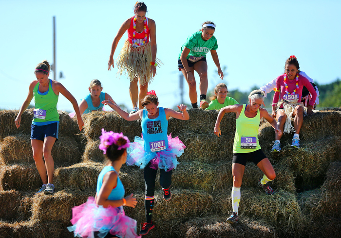 Marshfield-09/07/13 Participants in the Shape Diva Dash 5k obstacle race at the Marshfield Fairgrounds make their way over a hay bale obstacle along the course.