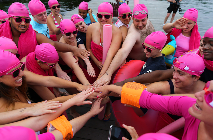 Boston-07/13/13 _The Charles River Conservancy hosted the 1st public swim in the Charles River in 50 years, as participants took the plunge at a boat dock near the Hatch Shell on the Esplanade. A group of swimmers from Education First joins hands before they swam