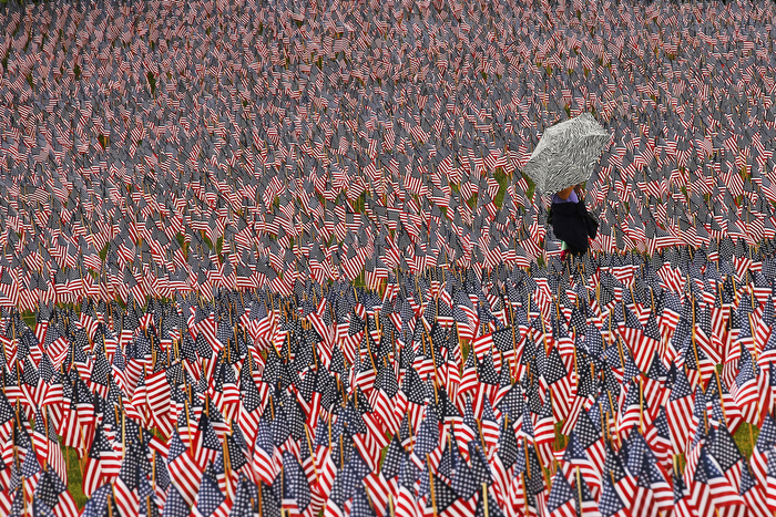 A pedestrian carrying an umbrella walks through a Memorial Day display of United States flags on the Boston Common in Boston, Massachusetts May 23, 2013.