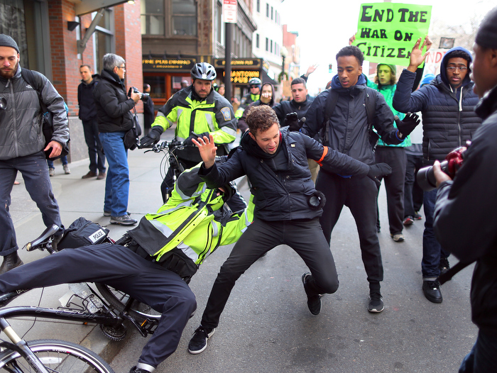 Boston--12/13/14- Thousands of protestors marched through the streets of Boston as part of the Black Lives Matter protest to bring attention to the recent police killings of unarmed blacks. A protestor is grabbed by a Boston Police officer on his bike after the protestor kicked his bike causing the officer to fall on Tremont Street. The police officer let him go.