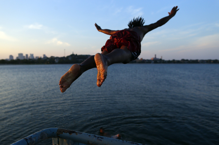 South Boston, Massachusetts -- 07/08/2014-- Edson Pontes, of Dorchester leaps off of a pier into Old Harbor in South Boston, Massachusetts July 8, 2014.