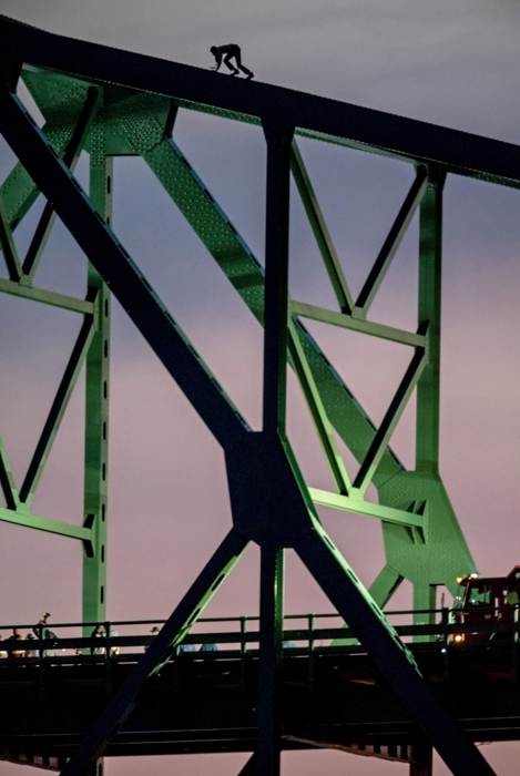 June 10, 2015-Boston,MA. USA. A man who police say was threatening to jump from Boston's Tobin Bridge, is seen climbing the bridge this evening as a police negotiator, bottom left, speaks to him through a microphone bull horn. The distraught man, who was seen by thousands of evening work commuters, climbed down shortly after sunset, after 2 hours atop the bridge.