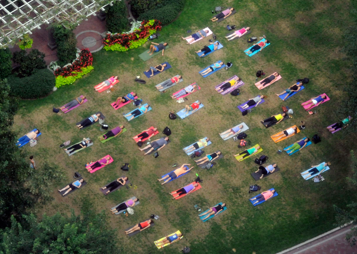 Colorful participants in an evening yoga appear to be taking a nap in a downtown Boston park on Monday, August 31, 2015.