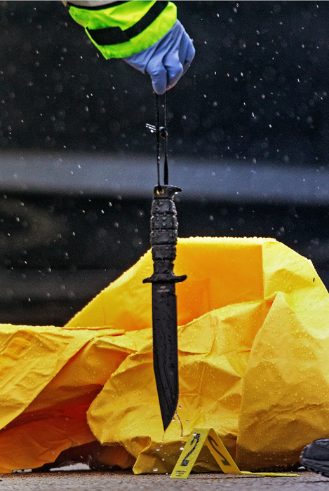 06/02/2015-Boston,MA. A Boston police detective hold a suspect's knife as he processes the scene of today's fatal police-involved shooting of a reported terror suspect. The man died after being confronted in this parking lot by police and members of the Joint Terrorism Task Force.
