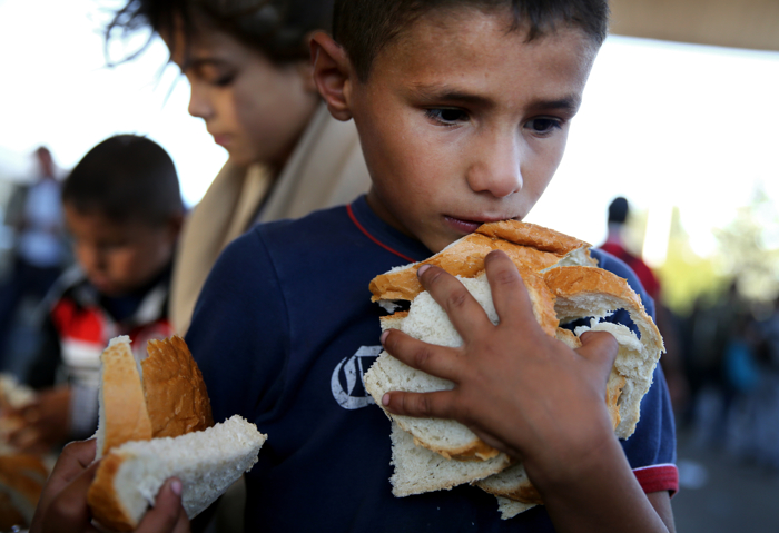 A young boy gathered as much bread as he could hold at an aid station before crossing the Austrian border outside of Hegyeshalom, Hungary. The migrants found a warm welcome from the Red Cross and a group of volunteers from Hungary, Austria and Germany. The United Nations estimates that more than half of the 4 million Syrian refugees worldwide are women and children. Migrants and refugees from Syria, Afghanistan, and other lands have fled en mass to Europe this year, in search of a better life. Four million refugees have fled Syria alone since a brutal civil war broke out after peaceful prodemocracy protests in 2011.
