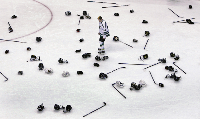 03/15/15: Boston MA: After the Westwood players celebrated their victory over Concord-Carlilse for the Division Two Boy's title, Westwood senior forward Patrick Forde faced a tall task as he looks for his discarded equipment amoung the multitudes of items littering the ice surface.