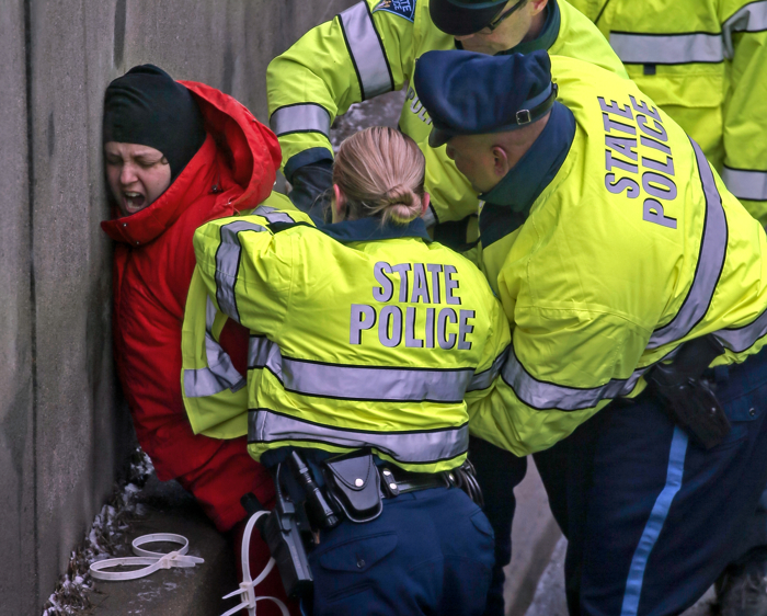 01/15/2015-Milton,MA A Black Lives Matter protester is arrested after blocking this morning's commute on route 93 north at East Milton Square. Several people exited 2 vans, laid down in the street as one of their arms, held in place by concrete, affixed to a large barrel. The morning commute was dramatically slowed for 2 hours.