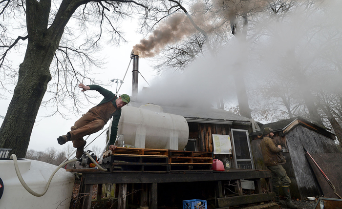 Rusty Varrell, 19, of Holliston, climbs down as steam from the evaporator and smoke from a wood fire pour from the Natick Community Organic Farm sugar shack. After a record slow start to the season, sap finally started to run from maple trees in Natick, Wellesley and Dover in mid-March . A combination of the heavy layer of snow and cold temperature made for a very short sugaring season.