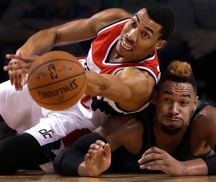 Washington Wizards forward Otto Porter Jr. and Boston Celtics center Jared Sullinger dive to the parquet floor while chasing a loose ball during the third quarter of an NBA game at TD Garden.