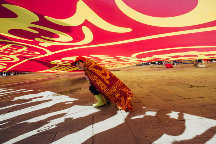 A boy plays beneath an oversized flag of the The Republic of San Marco during the festival of San Marco in Venice, Italy on April 25, 2016.