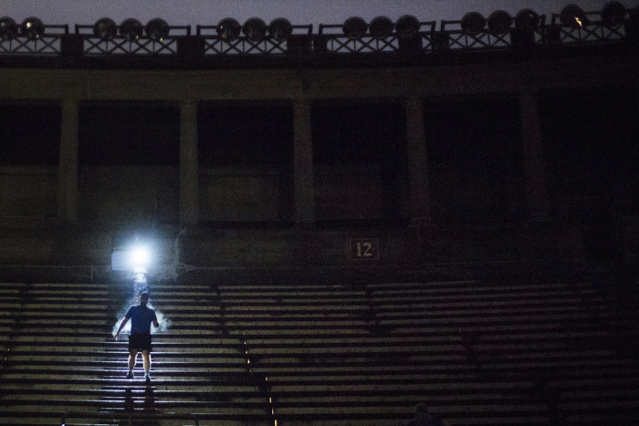 Nov. 30, 2016 — A member of the 5:30 a.m. section of the free exercise group The November Project is illuminated by a fellow runner’s headlamp as he scales the stone steps of Harvard Stadium.